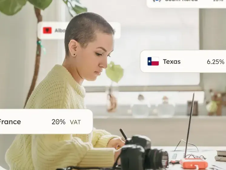 Creator at a desk with a camera and VAT rates for France and South Korea floating around